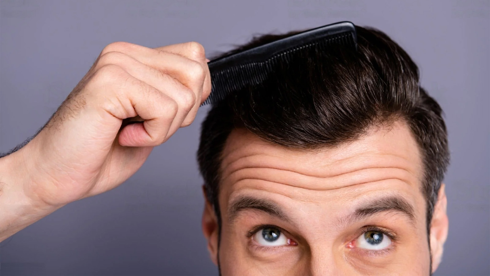 مردی در حال شانه زدن موی سرش